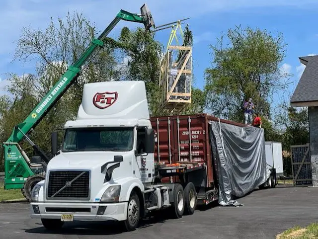 Truck unloading cargo with crane assistance.