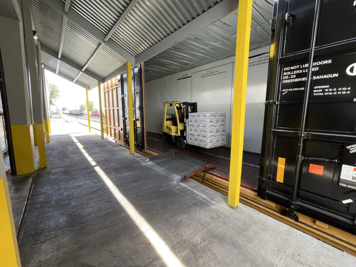 Forklift loading pallets into a shipping container.