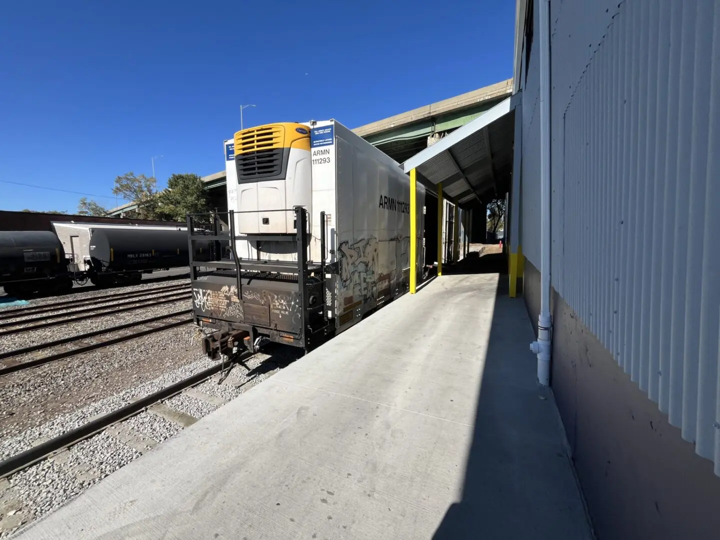 Train car beside industrial building platform.