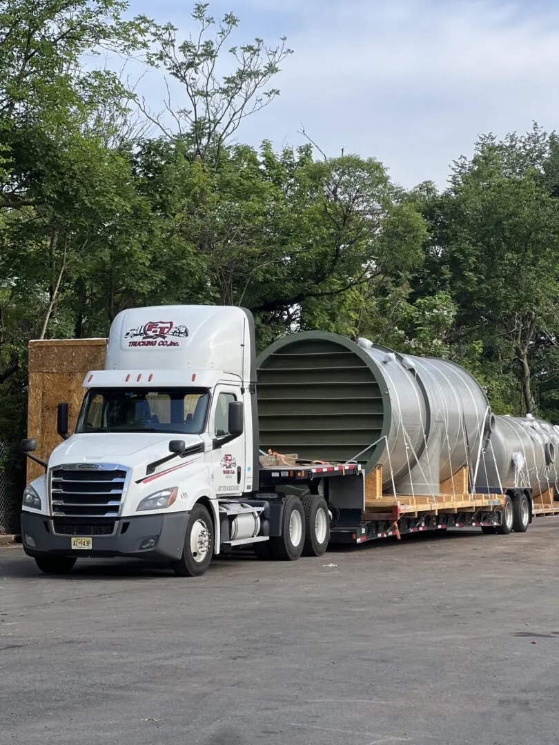 Truck transporting large cylindrical structures on trailer.