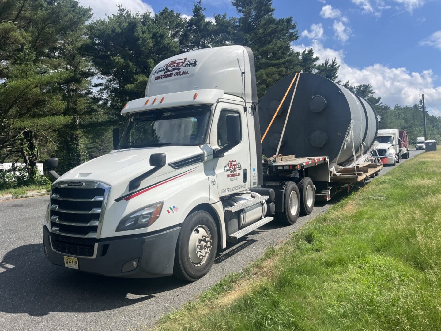 Truck transporting large industrial equipment on road.