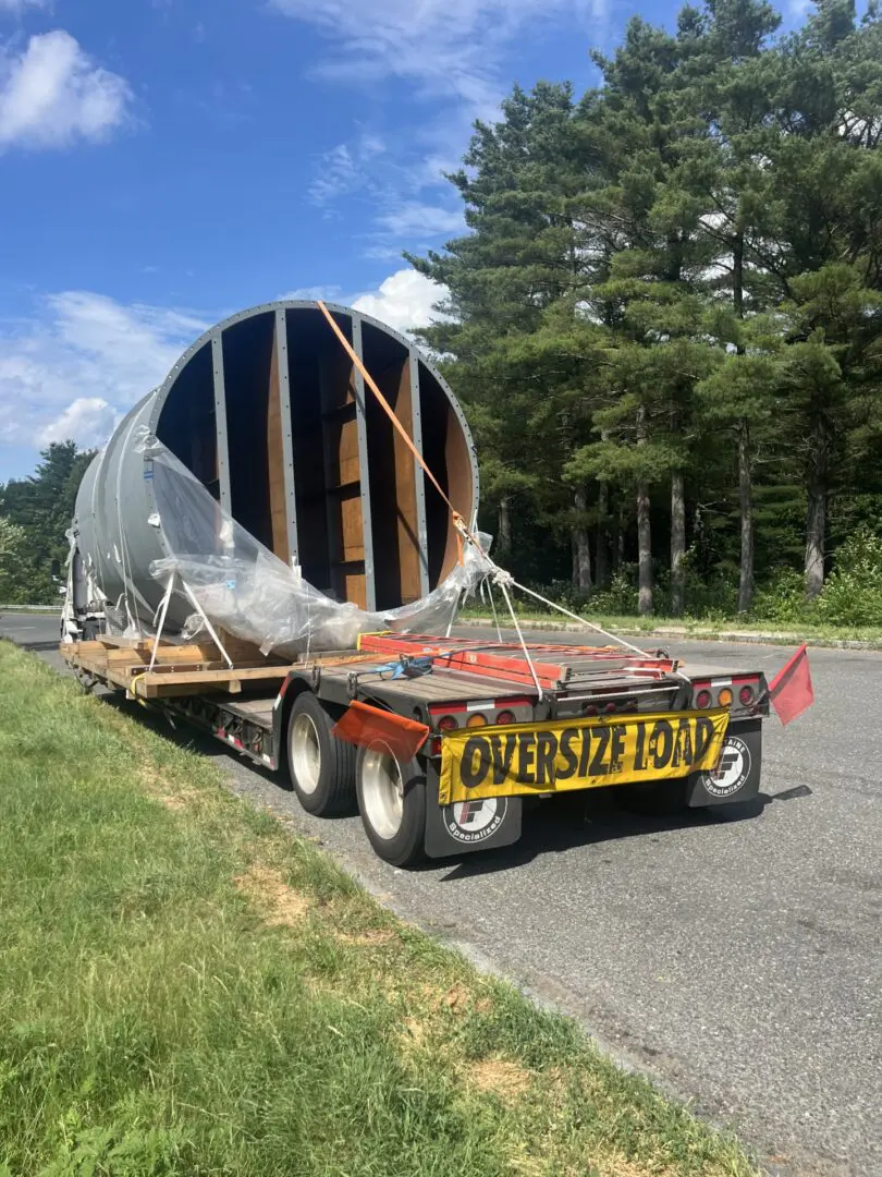 Oversized load on truck near trees.